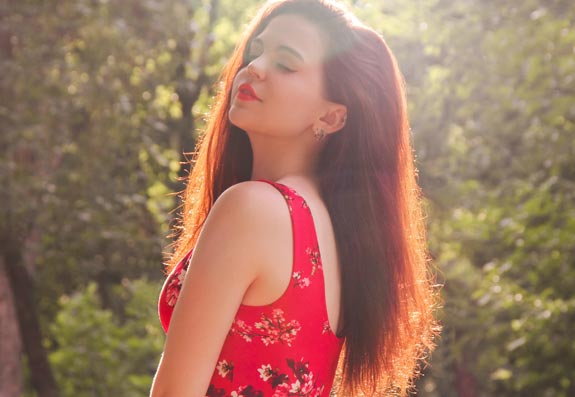 A photo of a woman in a floral-printed red dress posing in a field