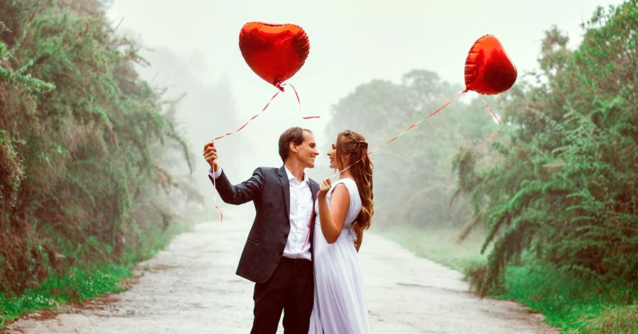 A couple holding red balloons. 